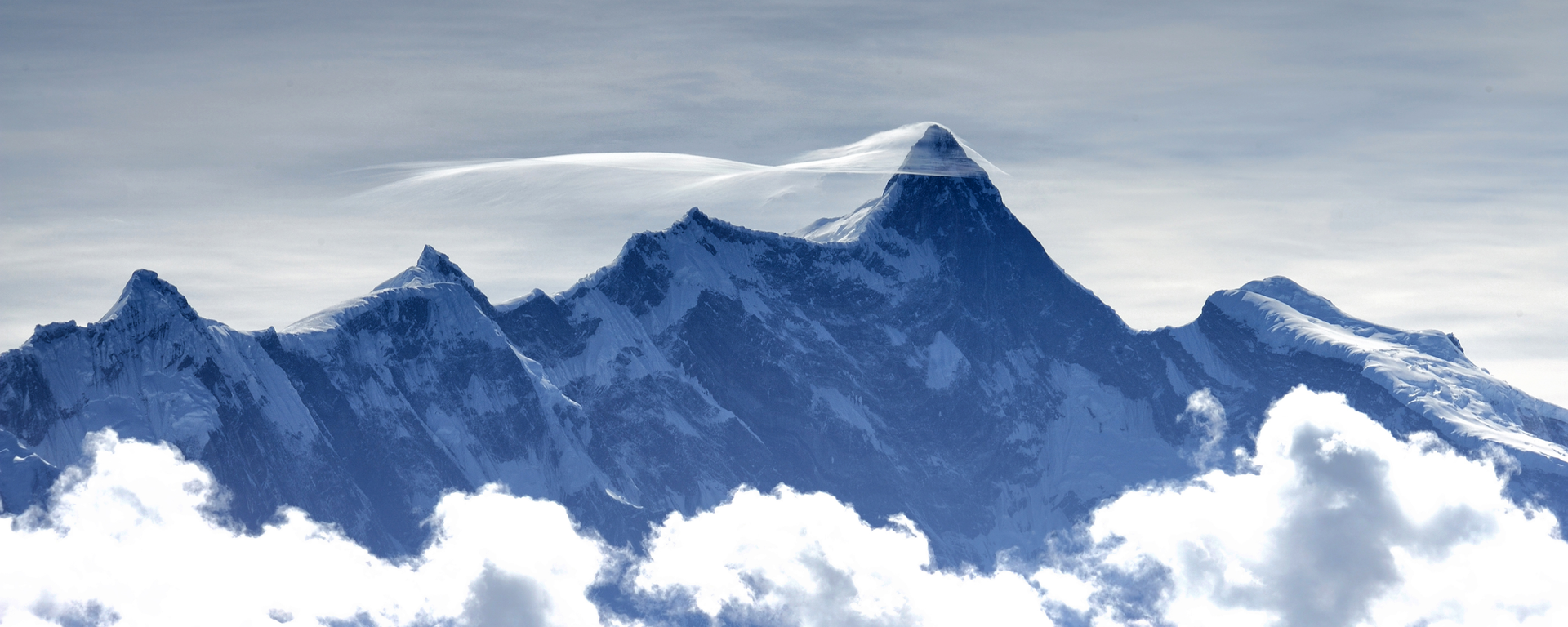 Snowy mountain peak with clouds in the foreground