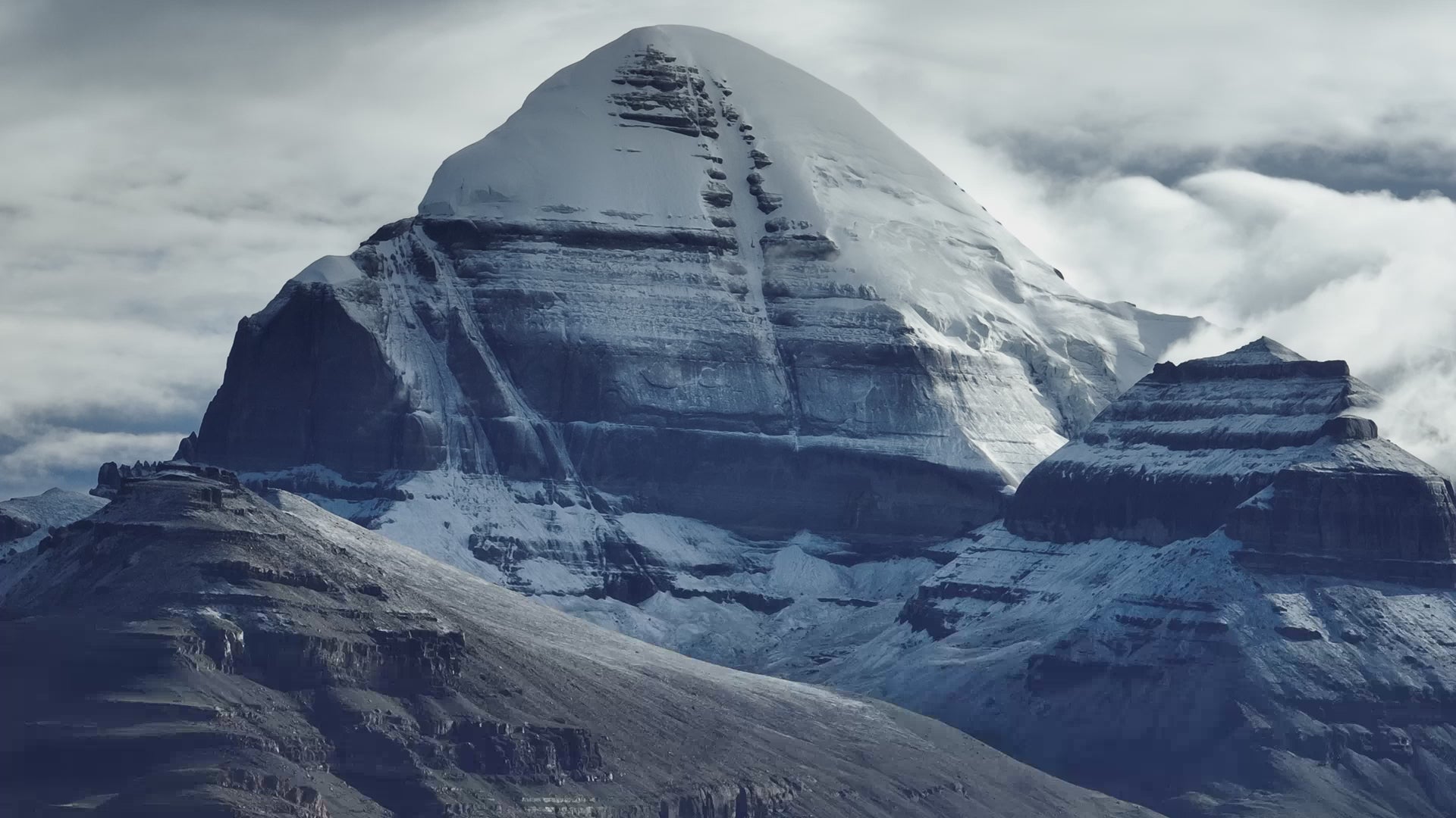 Mount Kailash rises between earth and sky, snow-crowned peak wrapped in ancient, untouchable mystery